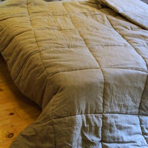 May include: A light brown linen duvet cover with a quilted pattern. The duvet is folded back on a bed with two pillows.
