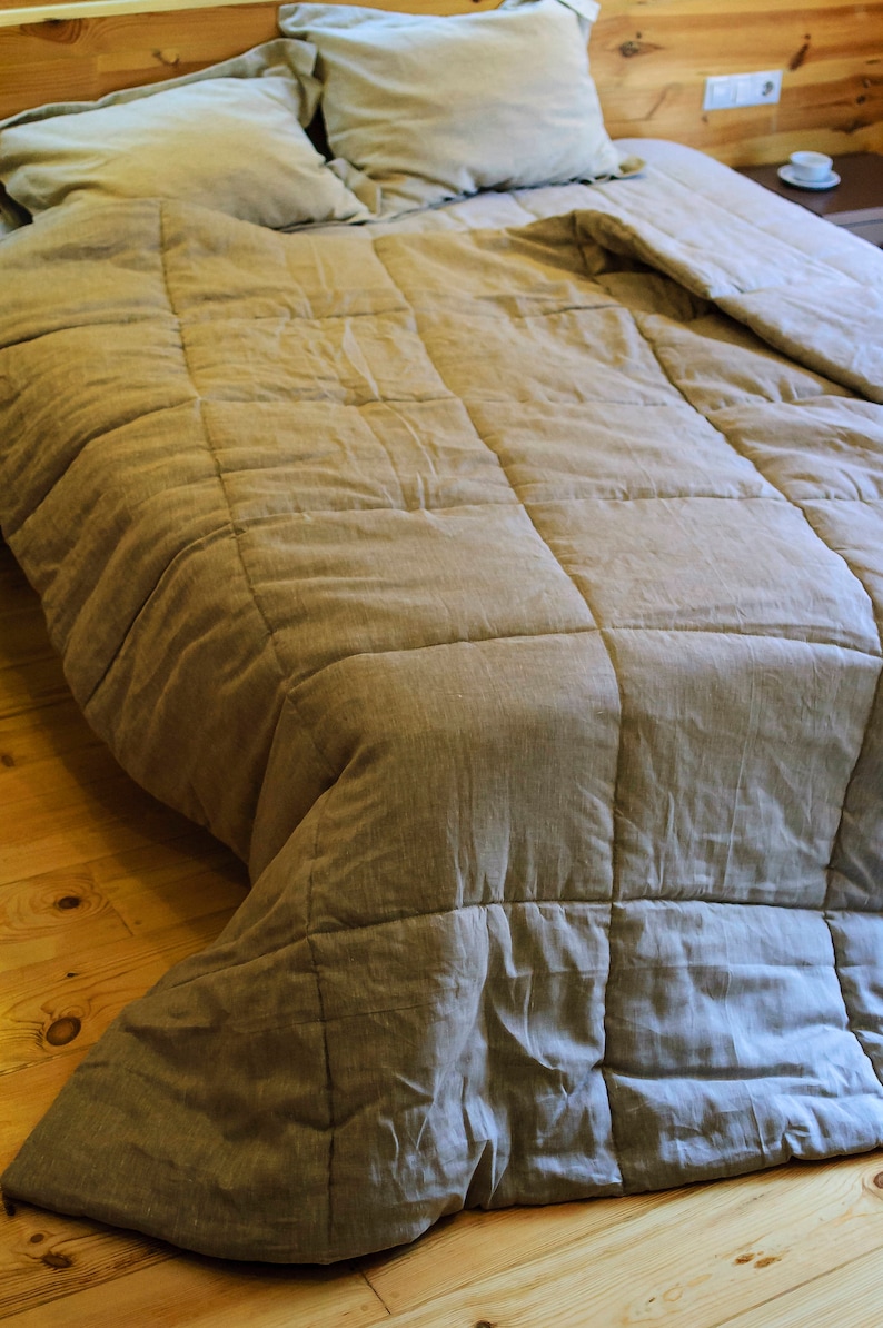 May include: A light brown linen duvet cover with a quilted pattern. The duvet is folded back on a bed with two pillows.