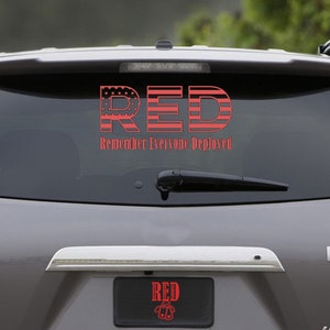 May include: A gray SUV with a red and white American flag sticker on the back window. The sticker says "RED" with the letters made of the American flag and the words "Remember Everyone Deployed" below. The car also has a license plate that says "RED" with a small American flag design.