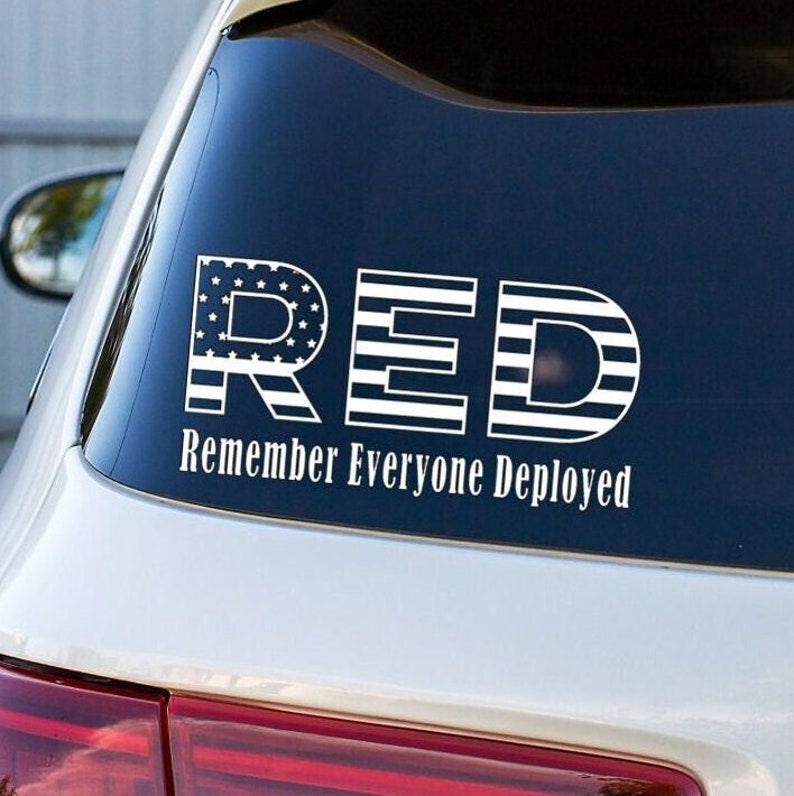 May include: A white vinyl sticker with the word "RED" in large letters, with each letter made up of an American flag design. The text "Remember Everyone Deployed" is below the word "RED".