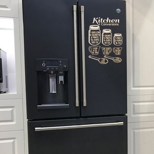 May include: Black refrigerator with a stainless steel handle and a white magnetic kitchen conversion chart on the right door. The chart shows the conversions for gallons, quarts, pints, cups, and ounces.