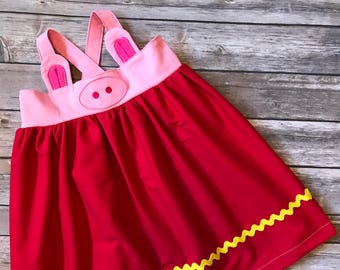 May include: A red dress with pink and white pig face details. The dress has yellow zig-zag trim around the bottom.