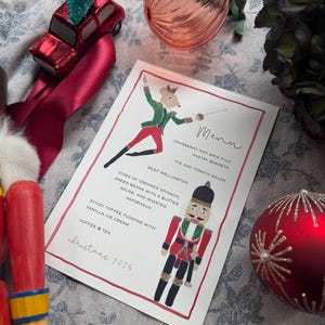 May include: A Christmas menu card with illustrations of a mouse fencer and a nutcracker soldier. The menu includes dishes like Beef Wellington and Sticky Toffee Pudding. The card is surrounded by Christmas ornaments and decorations.