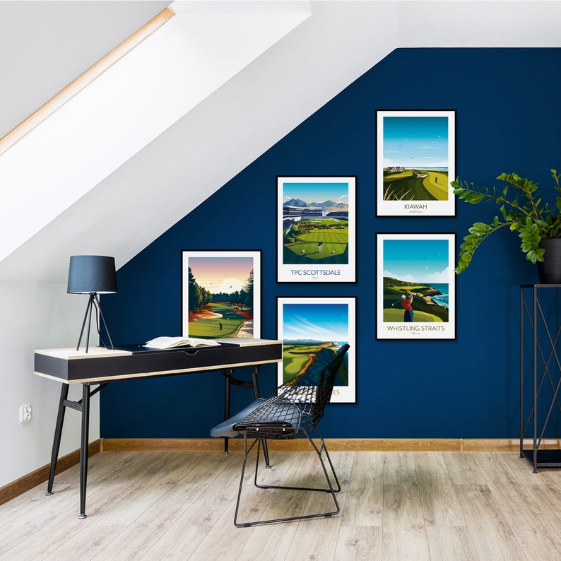 May include: Five framed golf course art prints hang on a dark blue wall. The prints feature scenic views of golf courses, including TPC Scottsdale, Kiawah, and Whistling Straits. A black desk with a lamp and a wire chair are in front of the wall.