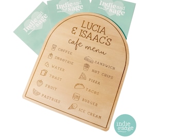 May include: A wooden sign with a rounded top, painted light brown, with the text "LUCIA & ISAAC'S cafe menu" in a brown font. The sign lists various food and drink items with corresponding icons, including coffee, smoothie, water, toast, fruit, pastries, sandwich, hot chips, pizza, tacos, burger, and ice cream.
