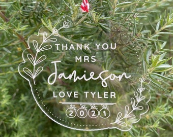 May include: Clear acrylic ornament with white text that reads "THANK YOU MRS Jamieson LOVE TYLER 2021". The ornament is round with a floral design and a red and white string for hanging.