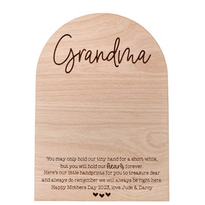 K&ouml;nnte beinhalten: Helle Holzplakette mit gew&ouml;lbter Oberseite. Das Wort "Grandma" ist in Schreibschrift geschrieben. Darunter ist eine herzliche Botschaft eingraviert, einschlie&szlig;lich "Happy Mothers Day 2023". Die Plakette ist ein sentimentales Geschenk.