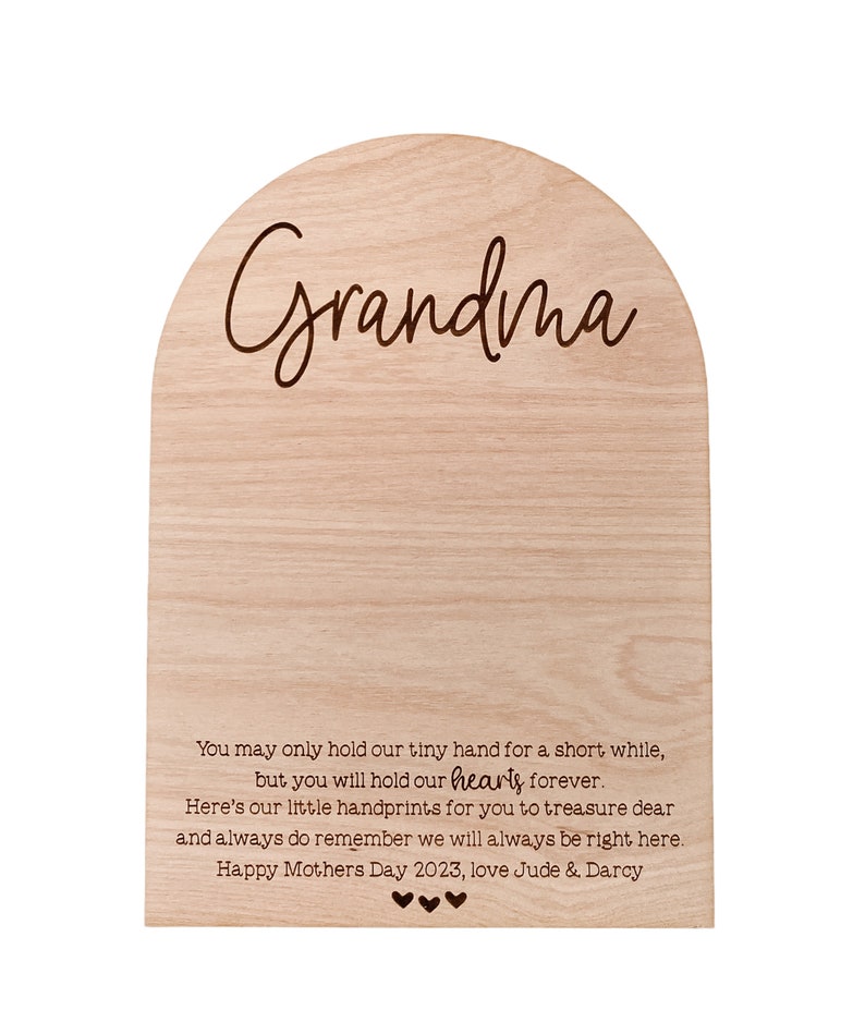 K&ouml;nnte beinhalten: Helle Holzplakette mit gew&ouml;lbter Oberseite. Das Wort "Grandma" ist in Schreibschrift geschrieben. Darunter ist eine herzliche Botschaft eingraviert, einschlie&szlig;lich "Happy Mothers Day 2023". Die Plakette ist ein sentimentales Geschenk.