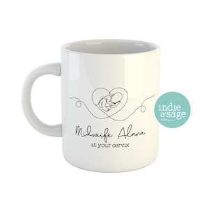 May include: White ceramic mug with a black line drawing of a baby in a heart shape. The text "Midwife Alana at your cervix" is printed on the mug.