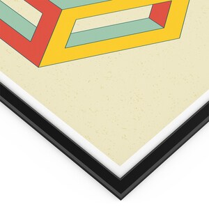 May include: A framed print of an abstract geometric design featuring a yellow, red, and blue cube with a white background.