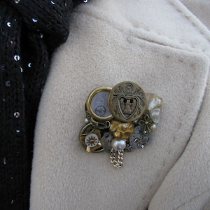 One knight at a time. Brooch featuring brass and gold buttons, mother of pearl, and watch parts in a gold wood frame