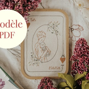 Peut inclure: Une broderie encadrée représentant une mère et son enfant, avec le mot "MAMA" en dessous. Le design est dans des tons bruns et beiges, avec des détails floraux et des motifs de cœur. Le texte "Modèle PDF" est dans un cercle en haut à gauche.