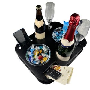 Könnte beinhalten: Ein schwarzes Tablett mit zwei Flaschenhaltern, zwei Glashaltern, einer kleinen Schale gefüllt mit bunten Pralinen, einem Handyhalter und einer Fernbedienung. Das Tablett befindet sich auf einem weißen Hintergrund.