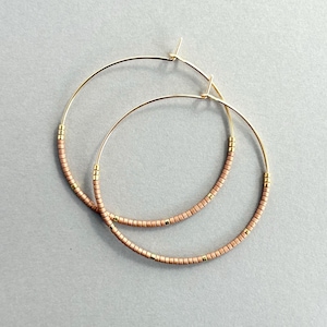 May include: A pair of gold hoop earrings with small, light pink beads.