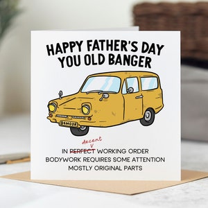 May include: A white card with a yellow cartoon car and the text "Happy Father's Day You Old Banger". The car has the text "94NGER" on the license plate. The text "decent" is crossed out and the text "perfect" is written above it. The text below the car reads "In perfect working order, Bodywork requires some attention, Mostly original parts."