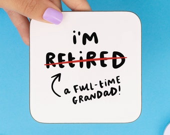 May include: White coaster with black text that says "i'm retired" with a red line through the word "retired" and an arrow pointing to the text "a full-time grandad!"