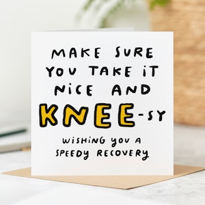 May include: A white card with black text that reads "MAKE SURE YOU TAKE IT NICE AND KNEE-SY WISHING YOU A SPEEDY RECOVERY". The word "KNEE" is in yellow.