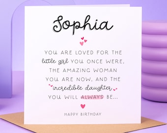 May include: A white card with a pink background. The card has black text that reads "Sophia" and "You are loved for the little girl you once were, the amazing woman you are now, and the incredible daughter you will always be... Happy Birthday".