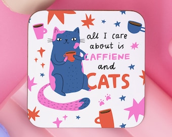 Puede incluir: Posavasos blanco con un gato azul sosteniendo una taza roja. El gato tiene manchas rosas y una cola rosa. El texto en el posavasos dice "all I care about is caffeine and cats".