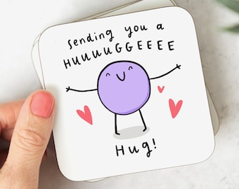 Può includere: Sottobicchiere bianco con un personaggio dei cartoni animati viola con le braccia aperte e il testo "Sending you a HUUUGGEE hug!" con tre cuori rossi.