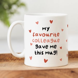 May include: White ceramic mug with the text "My favourite colleague gave me this mug!" in black lettering and surrounded by small red hearts.