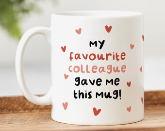 May include: White ceramic mug with the text "My favourite colleague gave me this mug!" in black lettering and surrounded by small red hearts.