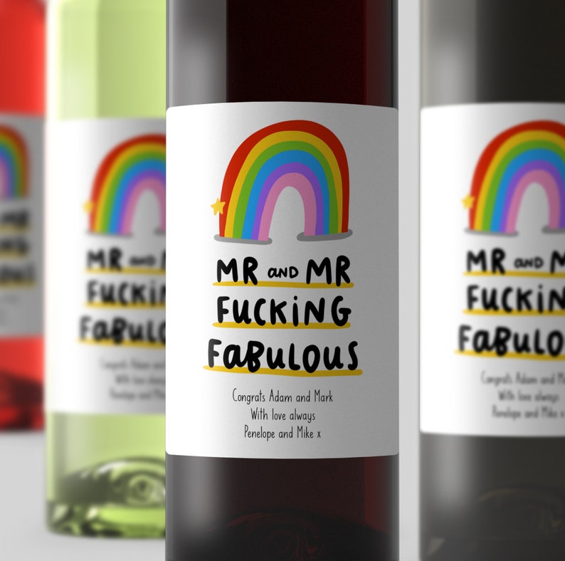 Puede incluir: Dos botellas de vino con etiquetas de arco&iacute;ris que dicen "Mr and Mr Fucking Fabulous". Las etiquetas tambi&eacute;n incluyen el texto "Congrats Adam and Mark, With love always, Penelope and Mike x".