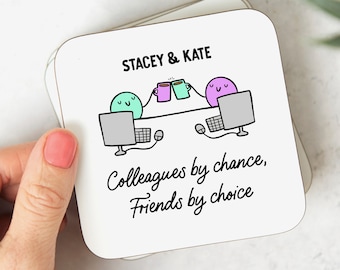 May include: White square coaster with a cartoon illustration of two friends at their computers, toasting with coffee mugs. The text reads "STACEY & KATE" and "Colleagues by chance, Friends by choice."