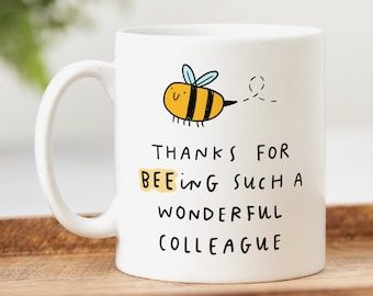May include: White ceramic mug with a cartoon bee illustration and the text "Thanks for bee-ing such a wonderful colleague".