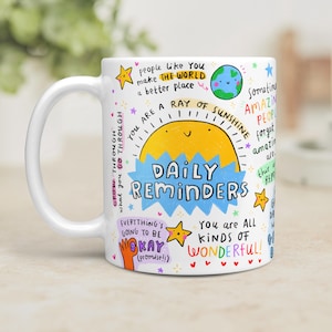 May include: White ceramic mug with colourful illustrations and text. The mug features a smiling sun, stars, and phrases like "Daily Reminders" and "You are a ray of sunshine." The design is whimsical and uplifting.
