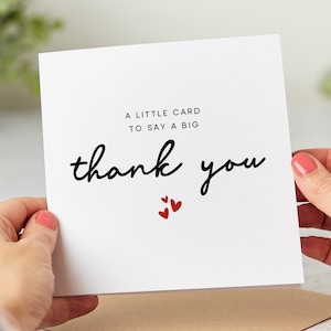 Puede incluir: Una tarjeta blanca con texto negro que dice "Una peque&ntilde;a tarjeta para decir un gran gracias". Tres peque&ntilde;os corazones rojos est&aacute;n debajo del texto.