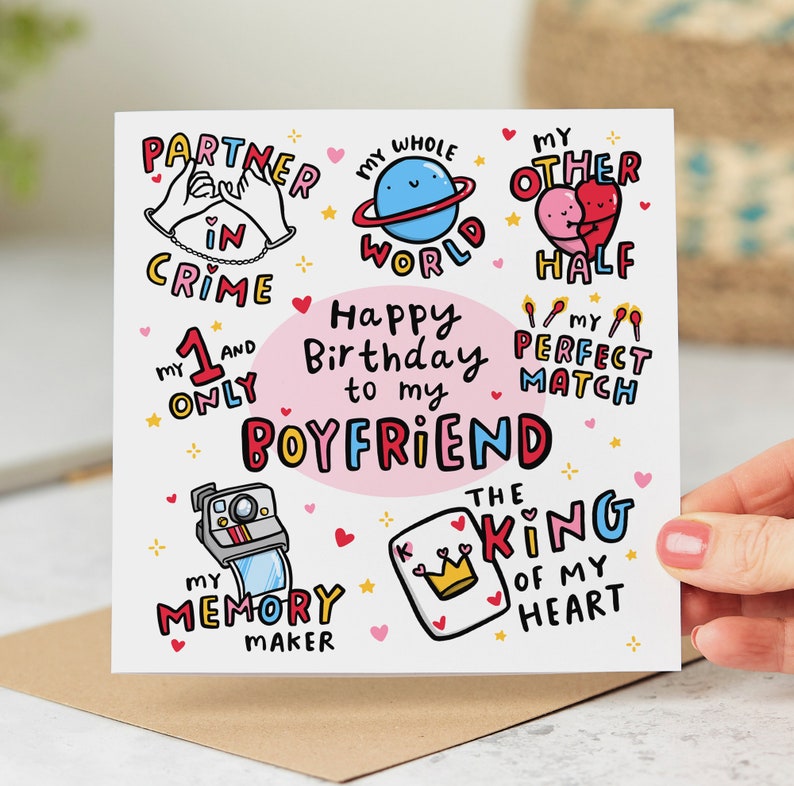 May include: A pink and white birthday card with colorful illustrations and the text "Happy Birthday to my Boyfriend". The card features phrases like "Partner in Crime", "My Whole World", "My Other Half", "My Perfect Match", "The King of My Heart", and "My Memory Maker".