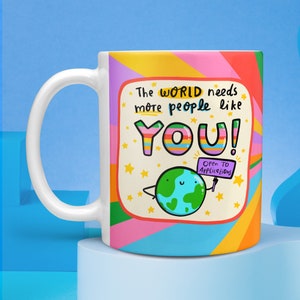 May include: White ceramic mug with a colorful design featuring a cartoon earth holding a sign that says "Open to Applications". The text on the mug reads "The world needs more people like YOU!"