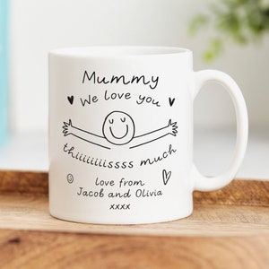 May include: White ceramic mug with a black hand-drawn illustration of a smiling person with outstretched arms. The text reads "Mummy &hearts; We love you &hearts; th iiiiiissss much  love from Jacob and Olivia XXXX &hearts;".