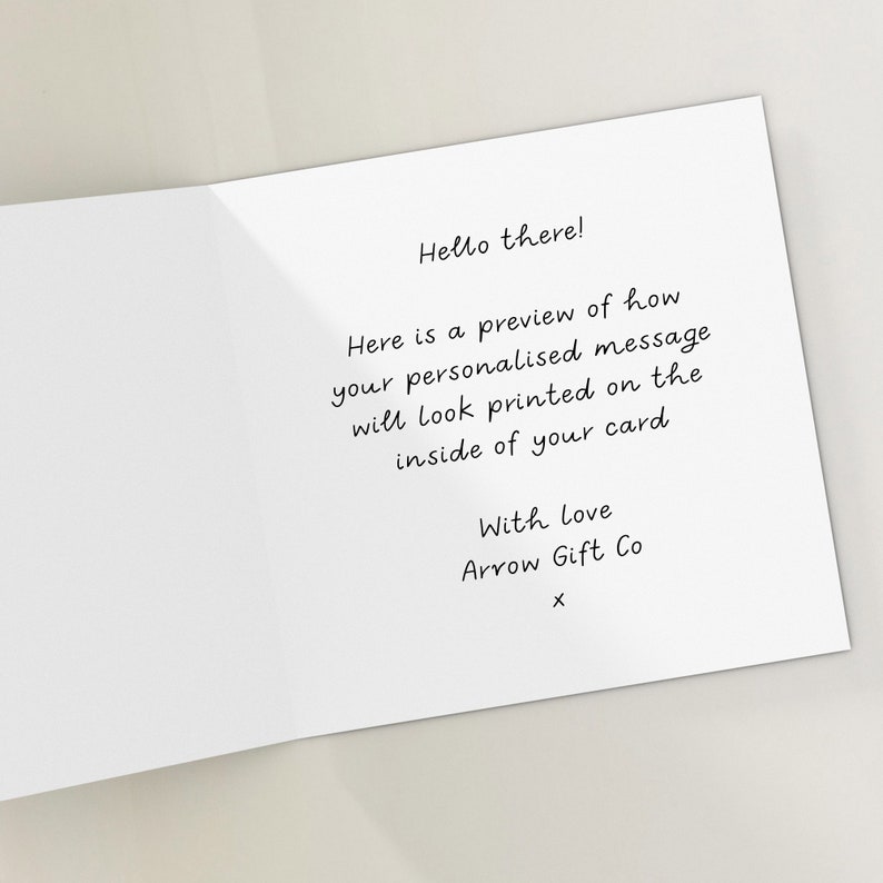 May include: A white card with black text that says "Hello there! Here is a preview of how your personalised message will look printed on the inside of your card With Love Arrow Gift Co X".
