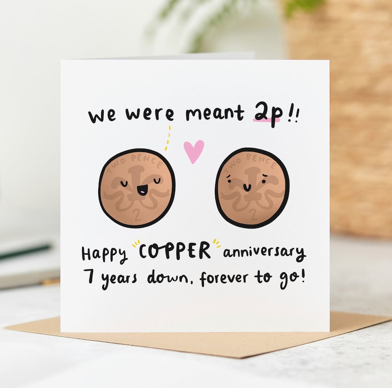 Puede incluir: Una tarjeta blanca con un coraz&oacute;n rosa y dos monedas de dibujos animados marrones con caras. El texto en la tarjeta dice "We were meant 2p!! Happy "COPPER" anniversary 7 years down, forever to go!"
