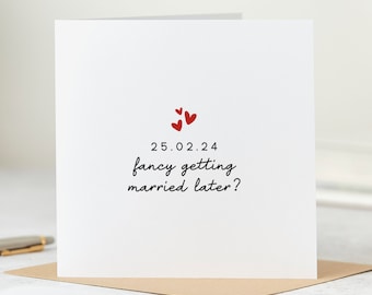 May include: White card with red hearts and the text "25.02.24 fancy getting married later?"