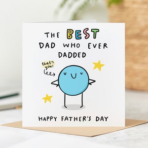 May include: A white card with a blue cartoon character with a happy face and the text "The Best Dad Who Ever Dadded" and "Happy Father's Day".