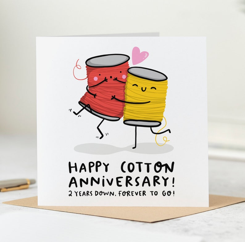 May include: A greeting card featuring a red and yellow cartoon spool of thread embracing each other. The card reads "Happy Cotton Anniversary! 2 years down, forever to go!"