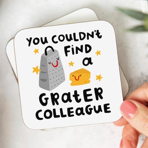 May include: White coaster with a black and white illustration of a grater and a piece of cheese. The text "You couldn't find a grater colleague" is written in black.