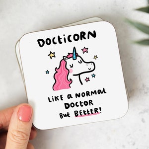 May include: White coaster with a cartoon unicorn with a pink mane and blue horn. The text reads "Docicorn like a normal doctor but better!"