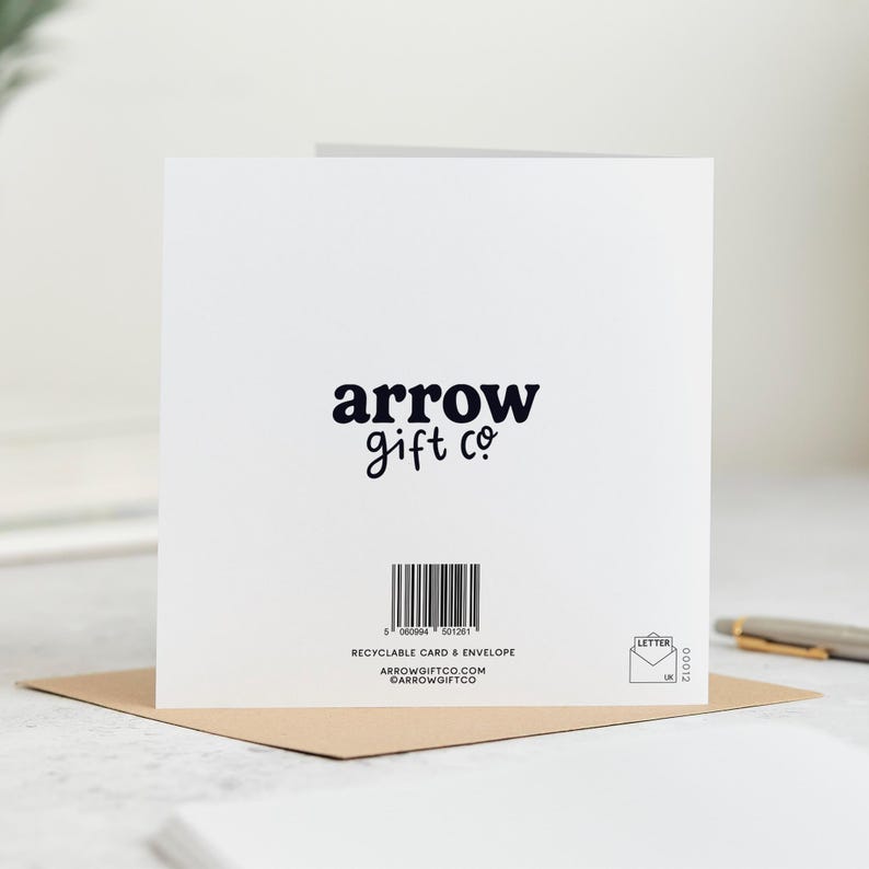 May include: A white greeting card with the text "arrow gift co" in black script. The card is on a brown envelope. A barcode and additional text are printed below the logo. The card is a letter size.