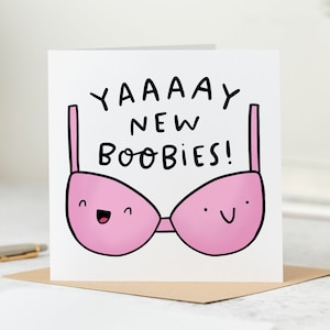 May include: A white card with black text that reads "YAAAAAY NEW BOOBIES!" and a pink bra with a smiling face on each cup.