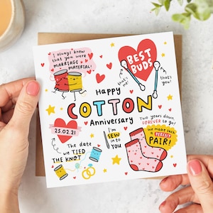 May include: A white card with a colourful illustration of a cotton anniversary card. The card features a red heart with the text "Best Buds" and two cotton buds. The card also features a red heart with the text "Happy Cotton Anniversary" and two spools of thread. The card also features a red heart with the text "The date we tied the knot" and two rings. The card also features a red heart with the text "I'm sew into you" and a needle and thread. The card also features a red heart with the text "Two years down, forever to go! We make such a perfect pair!" and two socks.