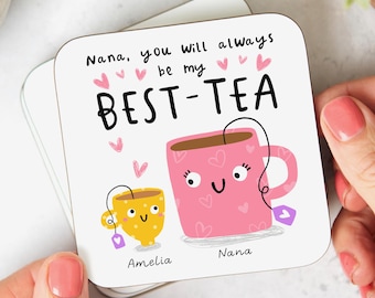 May include: White coaster with pink and yellow teacups with faces. The text reads "Nana, you will always be my BEST-TEA" with pink hearts. The teacups are labeled "Amelia" and "Nana".