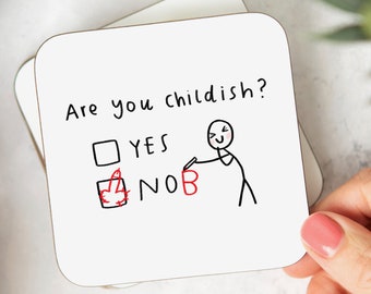 Puede incluir: Posavasos blanco con texto negro que dice "Are you childish?" con una casilla de verificación junto a la palabra "YES" y una casilla de verificación junto a la palabra "NO" con una marca de verificación roja en la casilla junto a "NO". Un palito está dibujado junto a la marca de verificación, sosteniendo un marcador rojo.