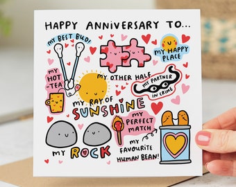 May include: A white card with a colorful illustration of hearts, a sun, a teacup, a puzzle, a rock, a match, and a can. The text on the card reads "Happy Anniversary To... My Best Bud, My Hot -Tea, My Other Half, My Ray of Sunshine, My Partner in Crime, My Perfect Match, My Rock, My Favorite Human Bean!"