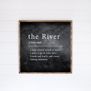 May include: Black chalkboard sign with a wooden frame. The sign says "the River ['river] noun a large natural stream of water; a place to go to relax, meet friends and family, and create lifelong memories."