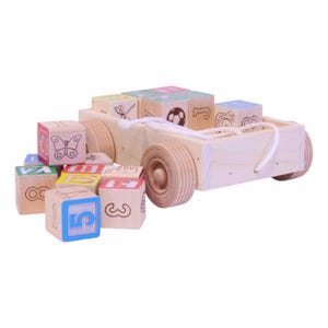May include: A wooden toy car with a white rope and wooden wheels. The car is filled with colorful wooden blocks featuring numbers, letters, and illustrations of a butterfly, a soccer ball, and other designs. The blocks are in various colors.