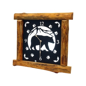 May include: A rustic wall clock with a black face featuring a bear silhouette, mountain scene, and paw prints. The clock is framed by a natural wood border, adding a touch of the outdoors to any room.